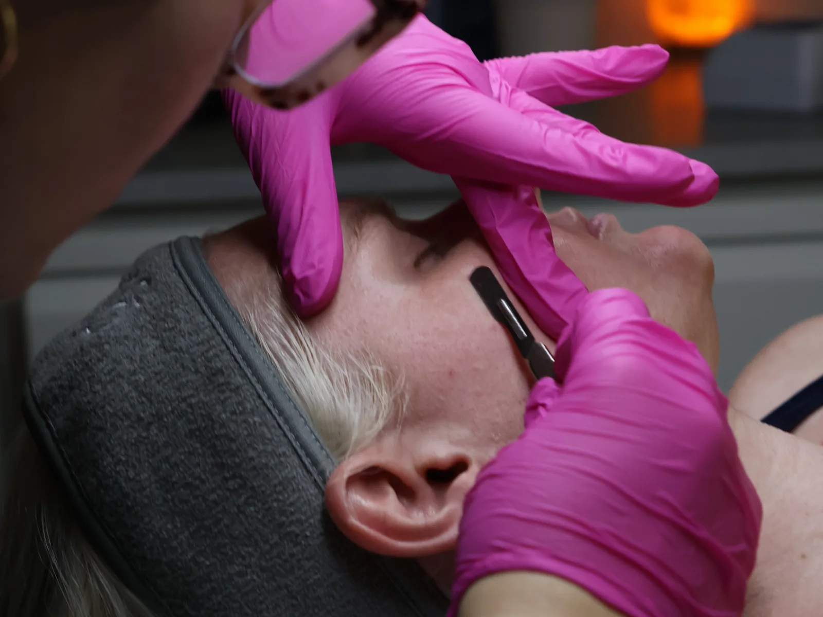 Jennifer dermaplaning a client’s face during a facial treatment.