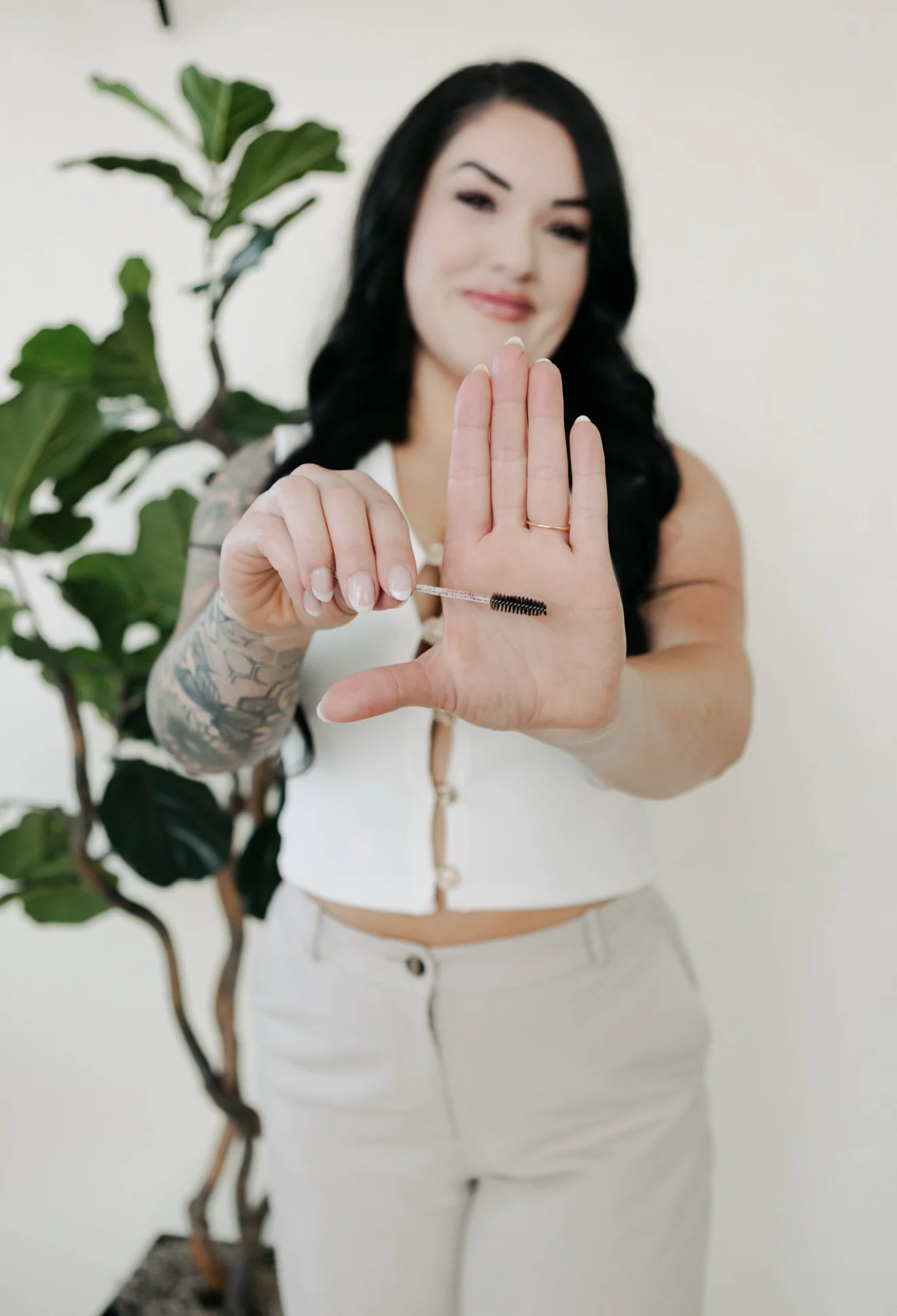 Jennifer holding a clean lash spoolie in the studio.