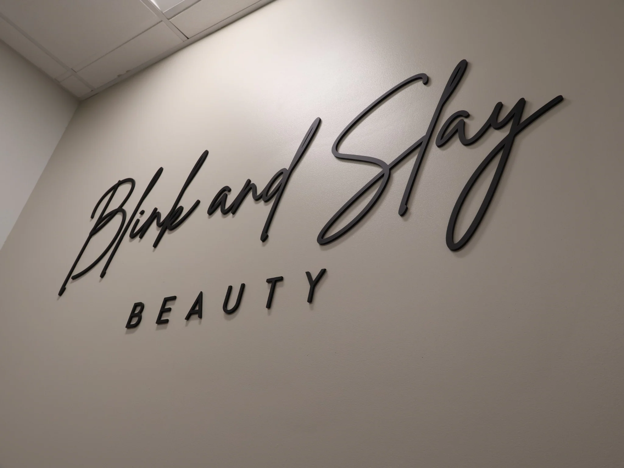Blink & Slay Beauty wall sign inside Jennifer's Denver studio.
